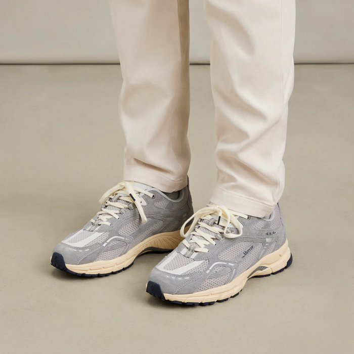 Gray sneakers worn with beige pants on a neutral background